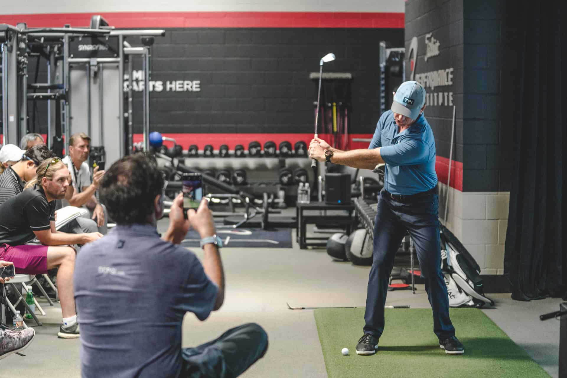 Chiropractor demonstrating golf swing mechanics during a sports performance and mobility assessment session
