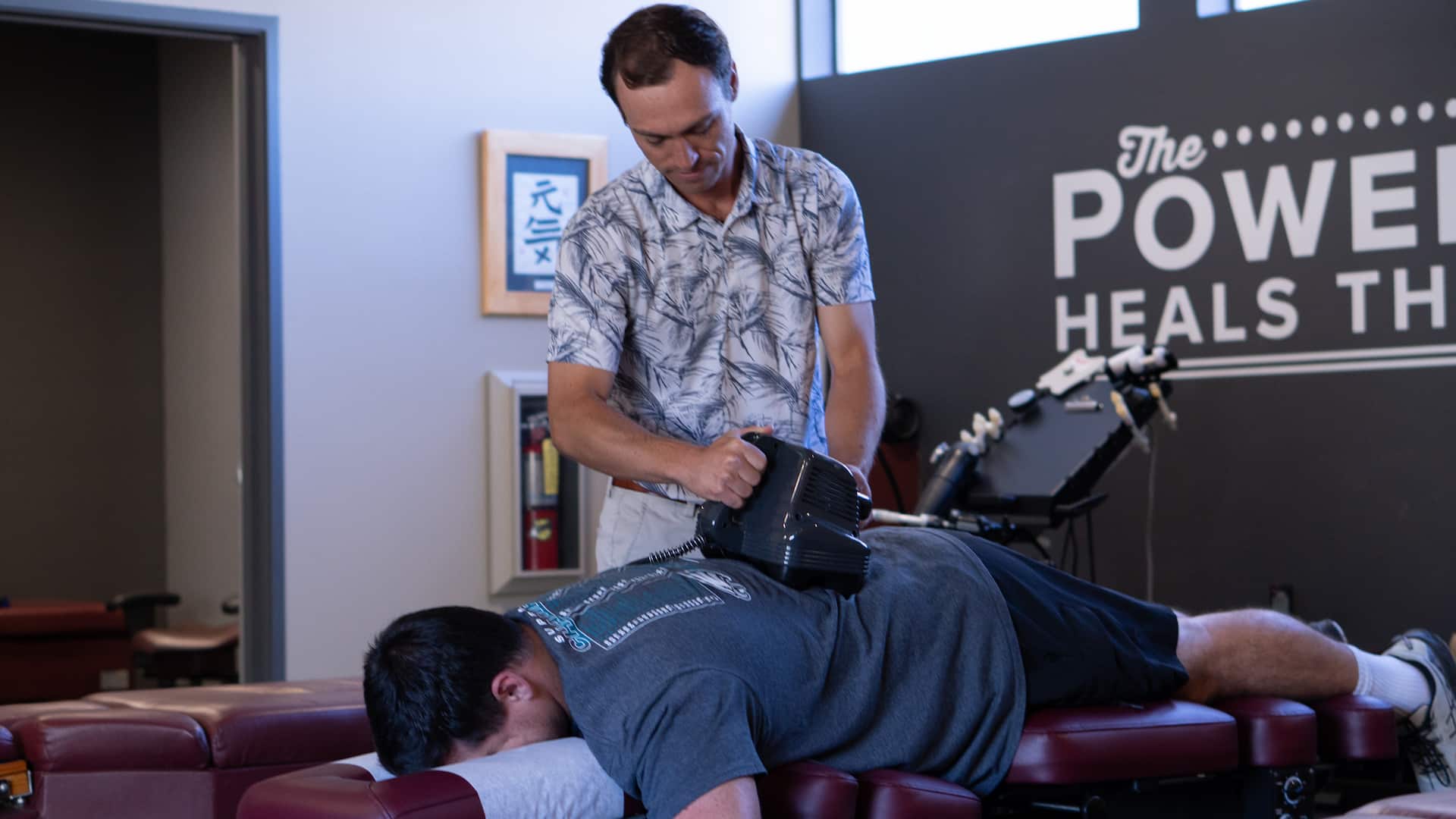 Chiropractor providing lower back pain treatment to a patient lying face down on a treatment table.