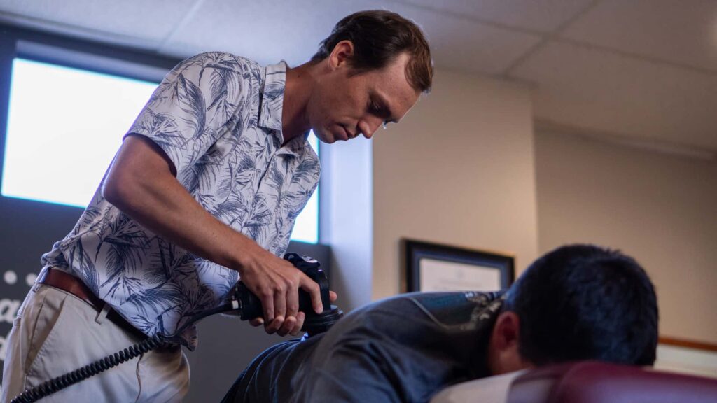 Dr. Riley Miller performing mid-back mobilization on a prone patient