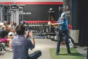 Chiropractor demonstrating golf swing mechanics during a sports performance and mobility assessment session
