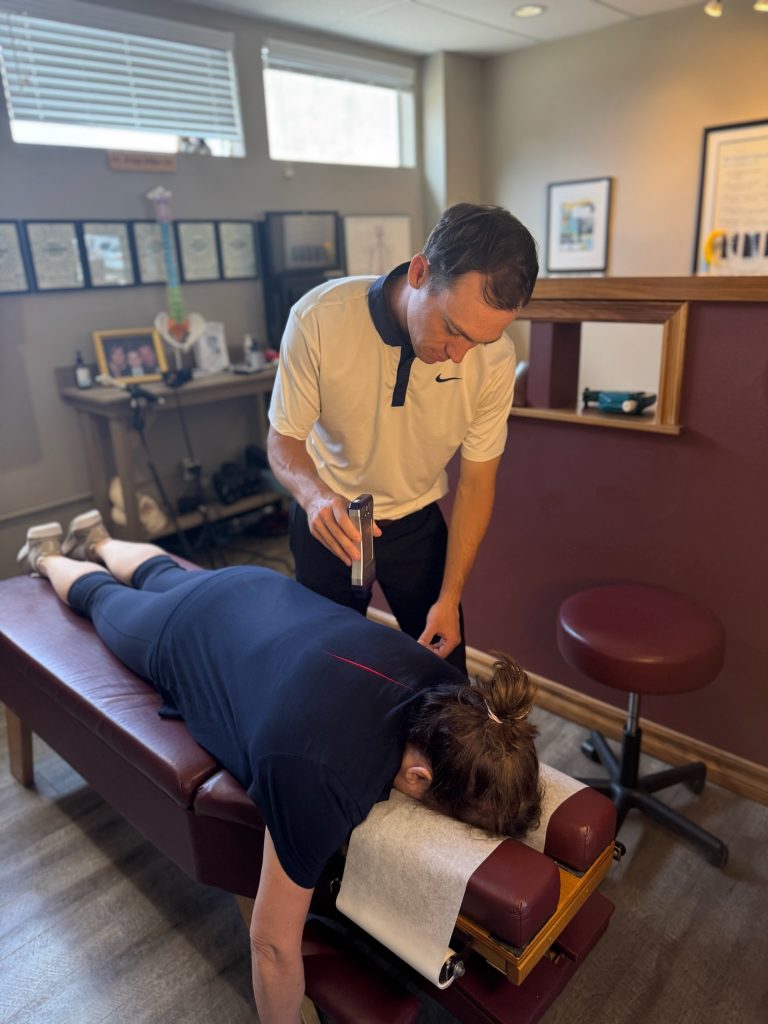 Dr. Riley Miller performing laser therapy on a female patient at the chiropractic place