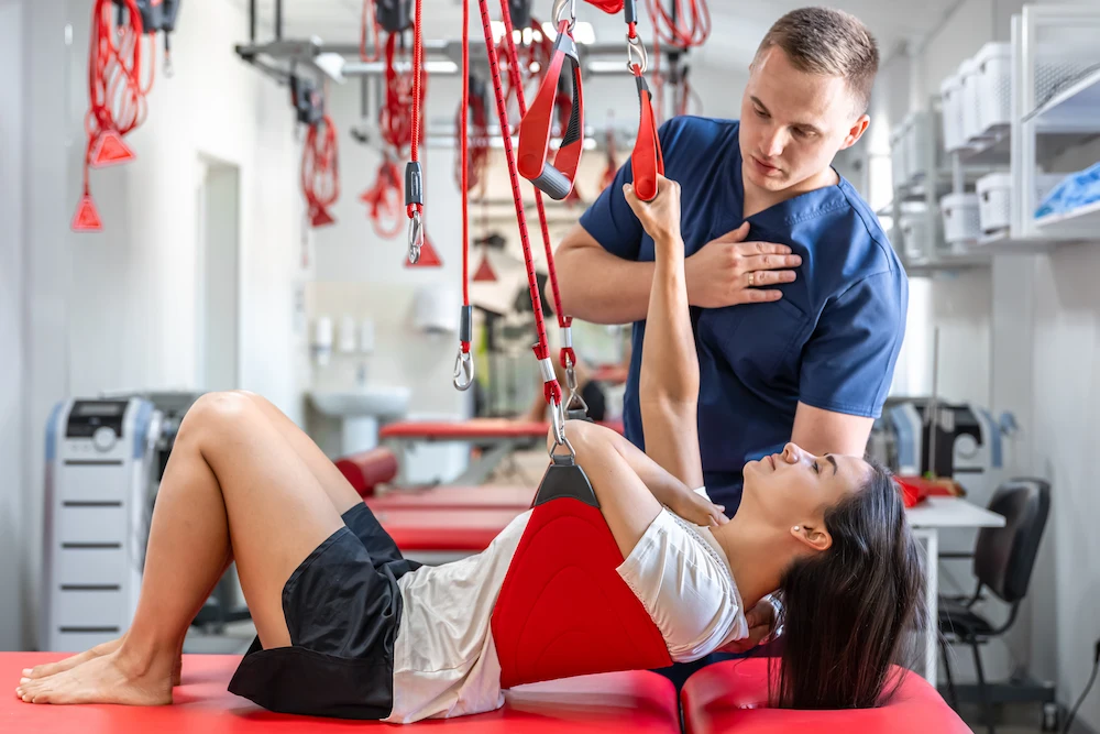 Therapist guiding patient through suspension strap rehabilitation exercise