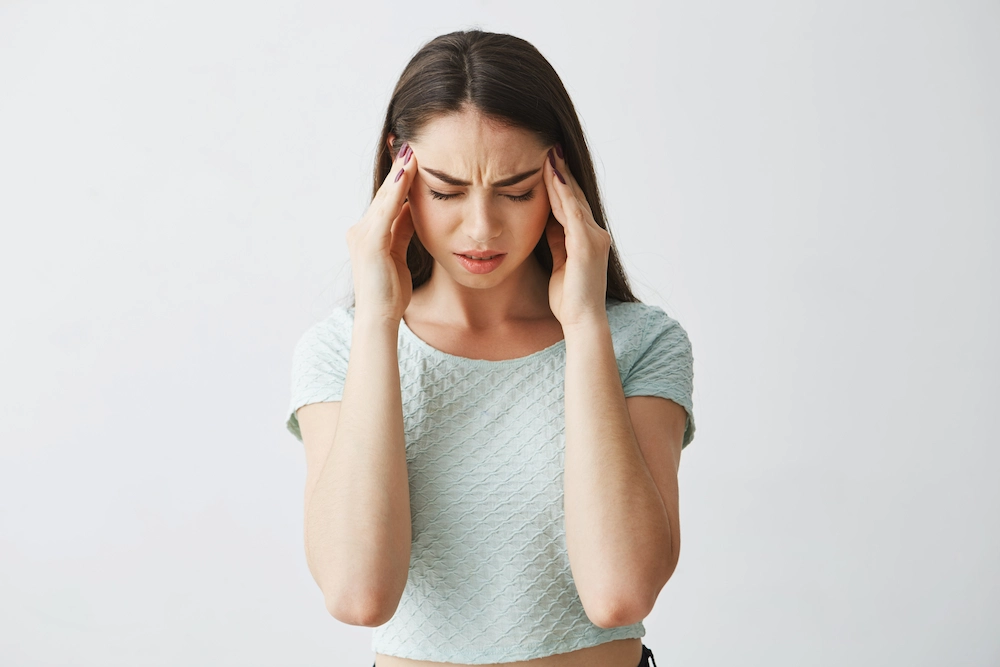 Young woman holding head due to chronic headache pain