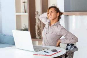 Office worker holding lower back due to work-related pain