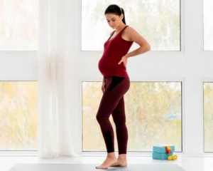 Pregnant woman experiencing back pain while supporting lower back for comfort
