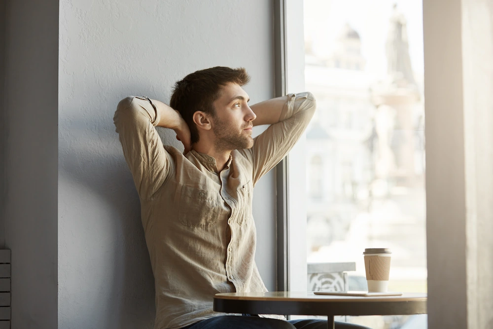 Person experiencing joint discomfort while looking out a rainy window